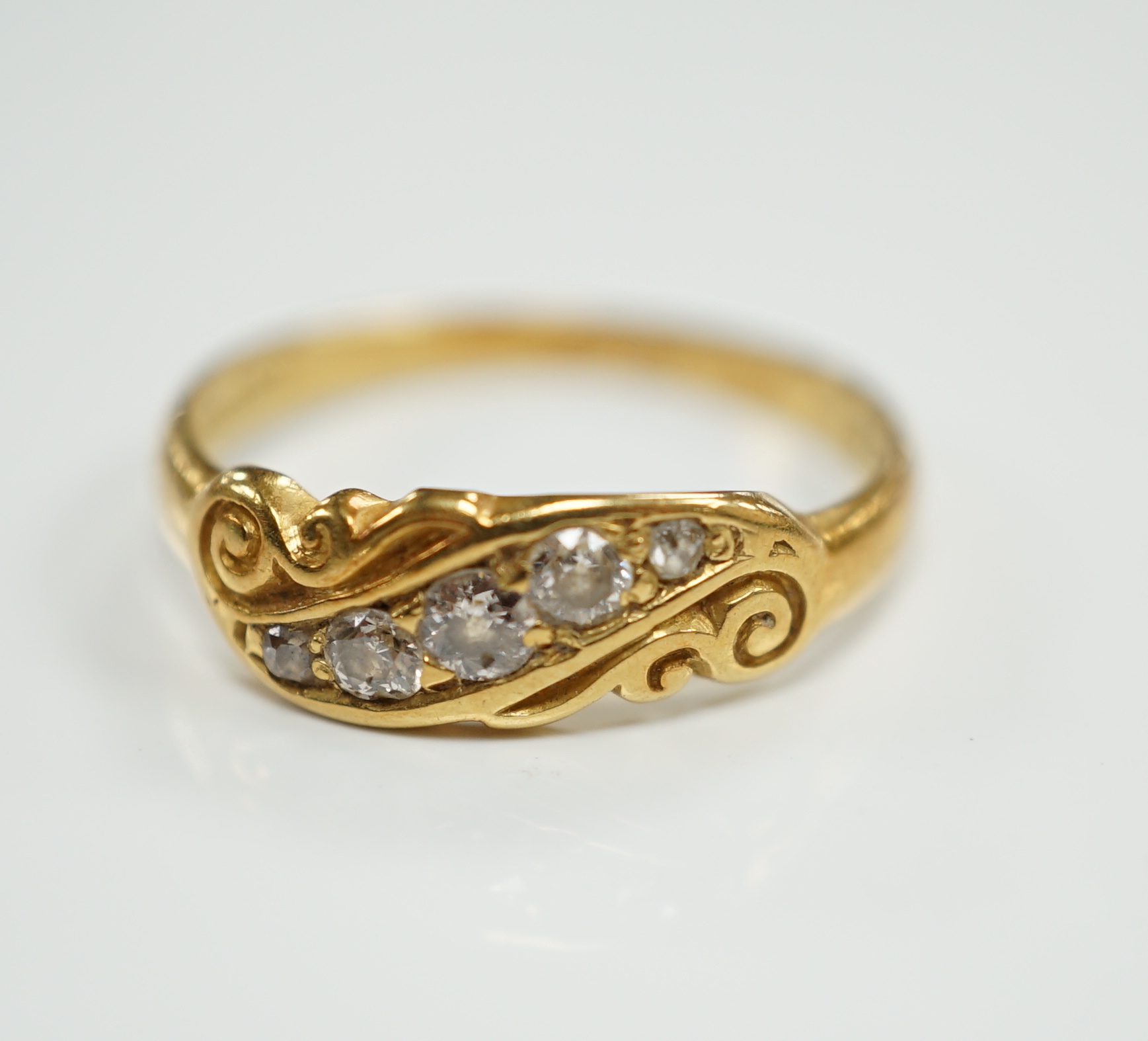 An early 20th century 18ct and graduated five stone set diamond ring, with scrolling setting, size Q, gross weight 3.4 grams.